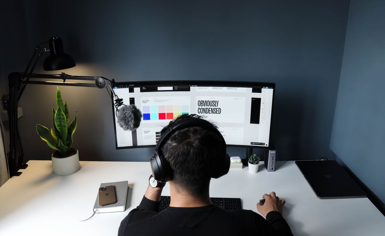 A man using a computer in a stylish home office with a minimalist setup.