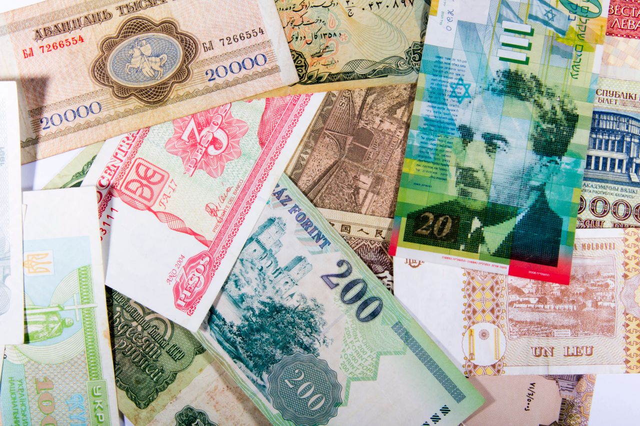 who-we-are Colorful assortment of international paper currencies from various countries in a flat lay.